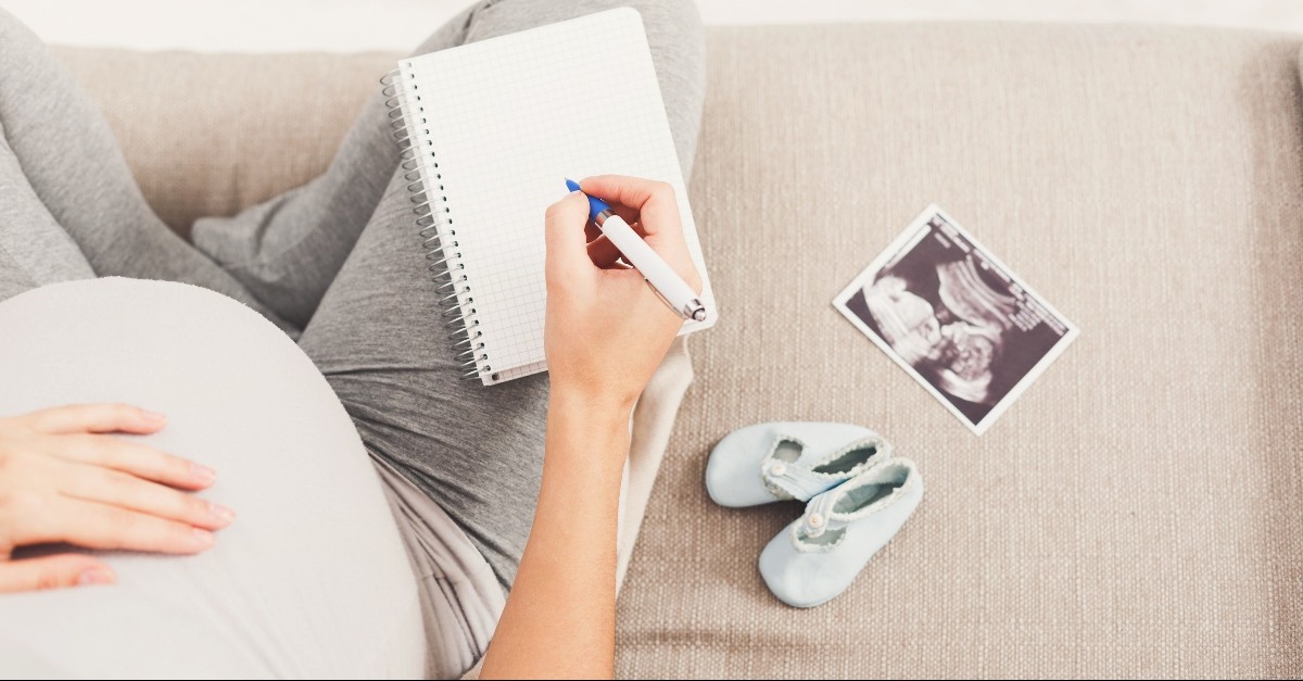 Pregnant woman on the couch with a sonogram and journals