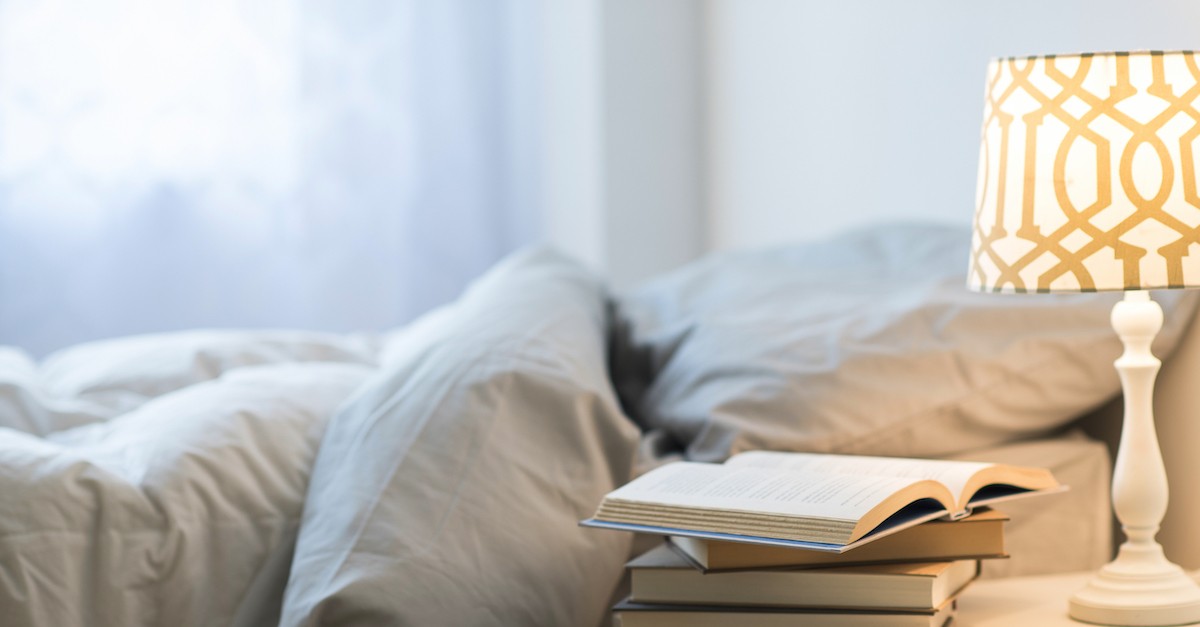 stack of books on nightstand by bed