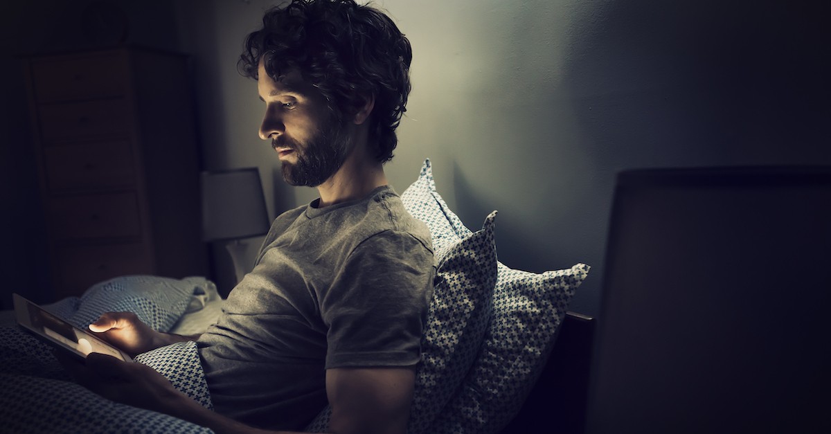 man reading tablet in bed